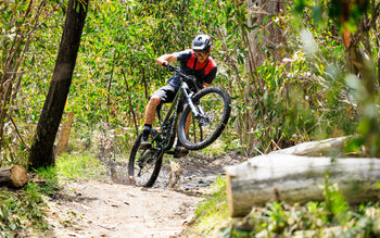 Rider manuals a Polygon Collosus N9 enduro bike through a muddy forest trail in Australia