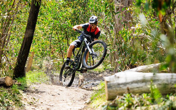 Rider manuals a Polygon Collosus N9 enduro bike through a muddy forest trail in Australia